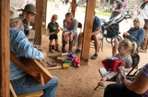 Paloma Sanchez, 3, from Austin, takes a squeezebox lesson from Terry Theis, a downtown street musician from Harper, who was playing the Kantsch. Sitting to Sanchez’ left just out of the frame is her grandmother, Francis, who was visiting from Paraguay. Strumming the guitar is Lee Haile. In the background, Boerne resident Owen, 3, with his mother and father Gabri and Paul Burgeson, plays with a blowing horn. His grandmother, Tracy Burgeson from Colorado, to the right, claps to the beat of the music.